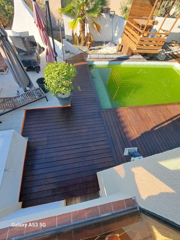Application d'un traitement de margelle en bois exotique sur une piscine à Lunel