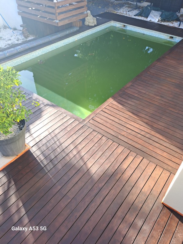 Application d'un traitement de margelle en bois exotique sur une piscine à Lunel