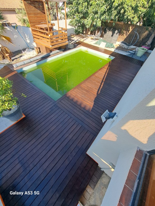 Application d'un traitement de margelle en bois exotique sur une piscine à Lunel