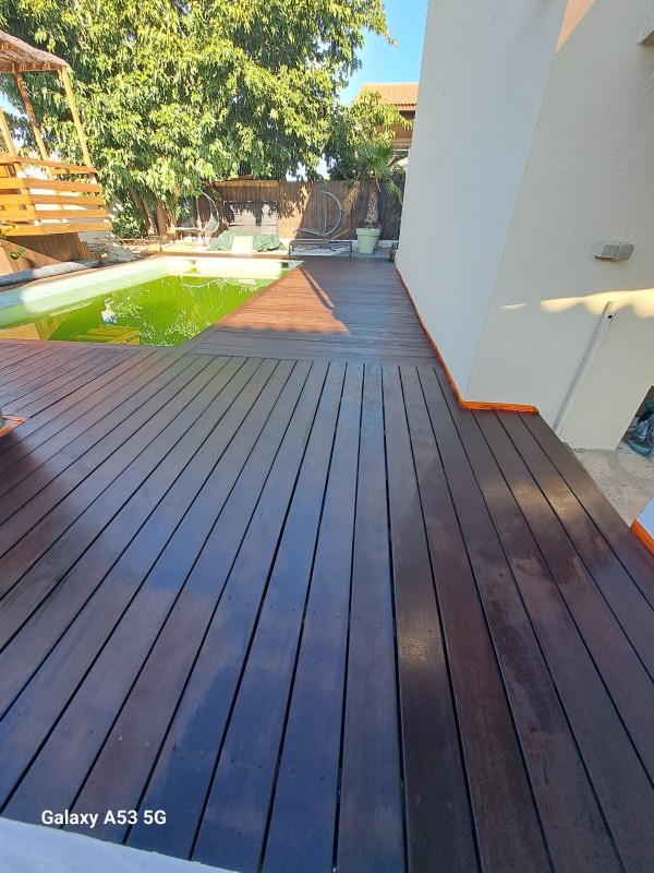 Application d'un traitement de margelle en bois exotique sur une piscine à Lunel